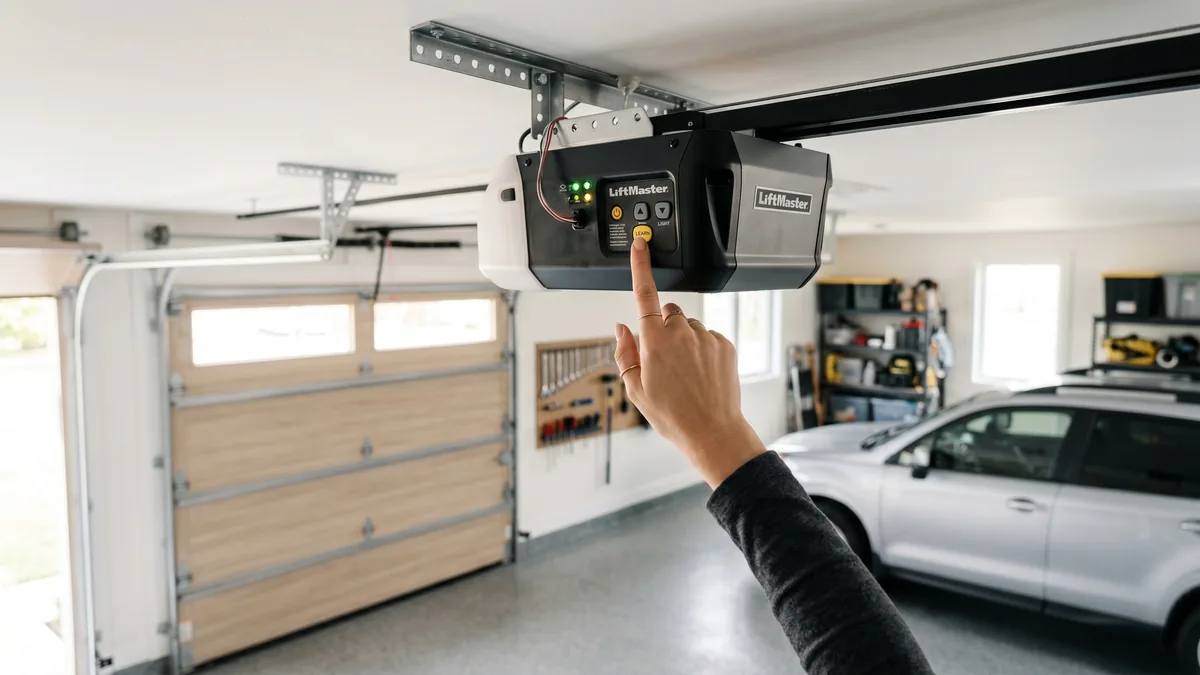Hand pressing the Learn button on a Chamberlain garage door opener motor head to program a remote