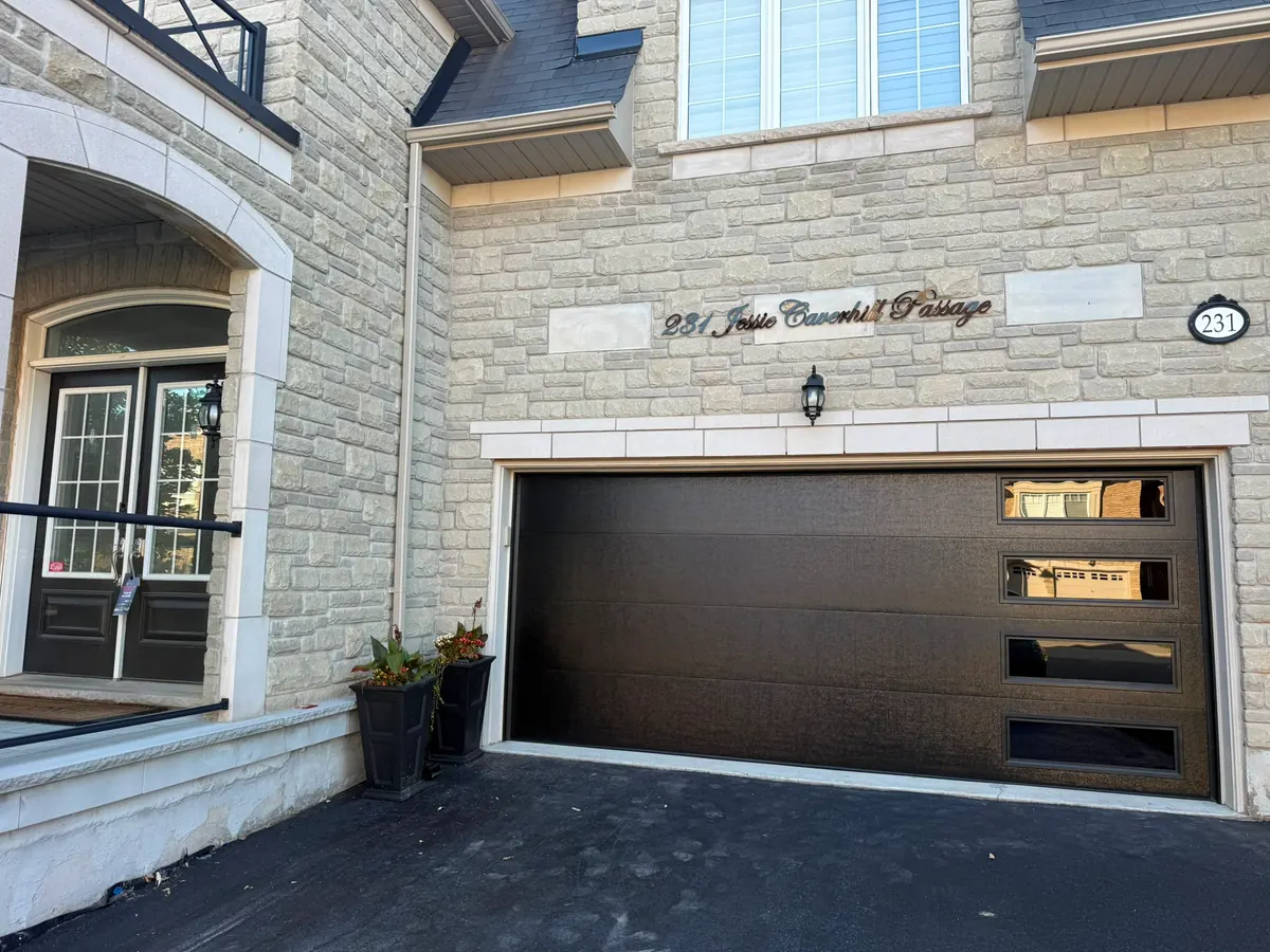 Dark brown modern flush-panel double garage door on a stone home
